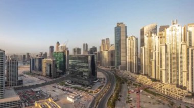 Gündoğumu sırasında Business Bay havacılık panoramik zaman diliminde modern kuleleri olan Bay Avenue, Dubai, BAE. Büyük otoparkın yakınındaki yolda trafiği olan gökdelenler.