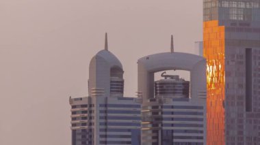Gün batımında Sheikh Zayed Yolu ve Dubai, BAE 'deki DIFC bölgesi hava zaman çizelgesinin etrafındaki yüksek binalarda. Cam yüzeyinden yansıyan güneşli Uluslararası Finans Merkezi gökdelenleri