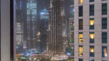 Dubai, Birleşik Arap Emirlikleri 'nde gece balkonlarında restoranları olan bir alışveriş merkezi. Kulelerde parlayan pencereler. Arka planında en yüksek gökdelen olan hava üstü görünümü