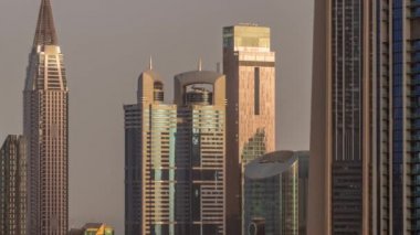 Sheikh Zayed Yolu etrafındaki yüksek binalar ve Dubai, BAE 'deki DIFC bölgesi zaman çizelgesi. Gündoğumunda cam yüzeyden yansıyan güneşli Uluslararası Finans Merkezi gökdelenleri