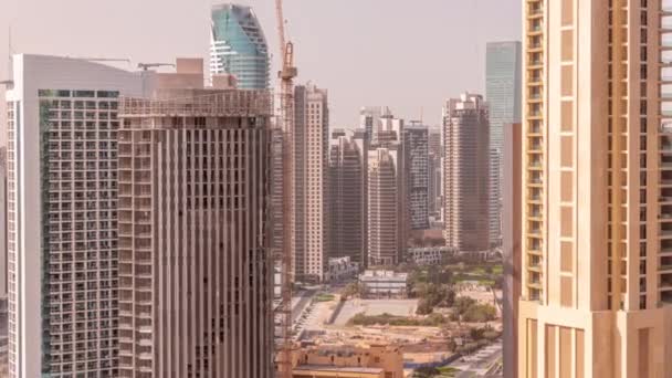 迪拜商业湾的摩天大楼在空中穿行 绿色草坪公园和配备起重机的新塔楼建筑工地 阿拉伯联合酋长国 — 图库视频影像