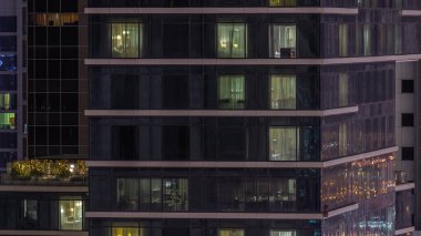Gece karanlığa bürünmüş gökdelen perdeleriyle kaplı bir daire penceresi şehrin ışıklarının yansıması havadan zaman ayarlı. Aydınlatılmış kuleler