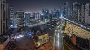 Panorama, Business Bay hava sahasında, Dubai, BAE 'de aydınlatmalı modern kuleler inşa edildiğini gösteriyor. Büyük otoparkın yakınındaki yolda trafiği olan gökdelenler.