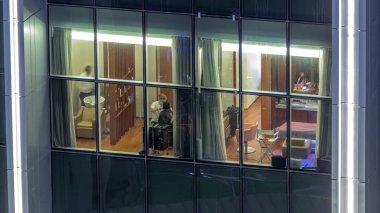 Kuaför salonu gece saatleri, berber dükkanında berberler gökdelenin aydınlık penceresinden saç kesiyorlar. Profesyonel berberler saç şekillendiriyor..