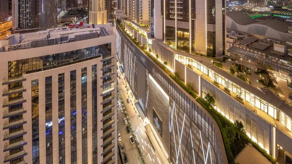 Road between tallest skyscrapers in downtown dubai located on bouleward street near shopping mall aerial night timelapse. Walking area with rooftop gardens