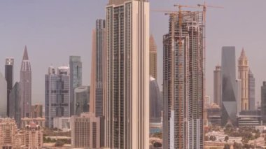 Dubai, BAE 'de tüm gün boyunca Sheikh Zayed Yolu ve DIFC bölgesi panoramik zaman dilimi çevresindeki yüksek binalar. Gölgeleri hızla hareket eden Uluslararası Finans Merkezi gökdelenleri