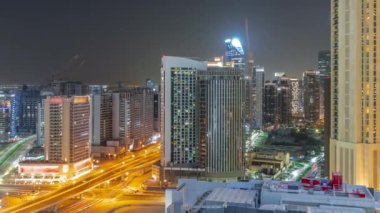 Dubai 'deki Business Bay hava sahasındaki gökdelenler tüm gece boyunca panoramik zaman diliminde ışıklar kapalıyken. Turnalı yeni kulelerin kesişme ve inşaat sahası, Birleşik Arap Emirlikleri