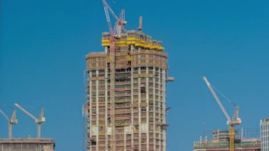 Karmaşık bir hava zaman diliminin inşaat süreci. Açık mavi gökyüzünün arka planına karşı pek çok yüksek katlı vinç ve inşaat halindeki yeni binalar.