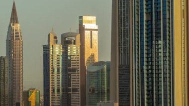 Güneş, Dubai, BAE 'de gün doğumu sırasında Sheikh Zayed Yolu ve DIFC bölgesi hava zaman dilimi çevresindeki yüksek binalardan yansımaktadır. Cam yüzeyi olan Uluslararası Finans Merkezi gökdelenleri