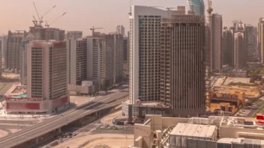 Dubai 'deki Business Bay' deki gökdelenler panoramik zaman dilimi boyunca gölgeler hızla hareket ediyor. Turnalı yeni kulelerin kesişme ve inşaat sahası, Birleşik Arap Emirlikleri