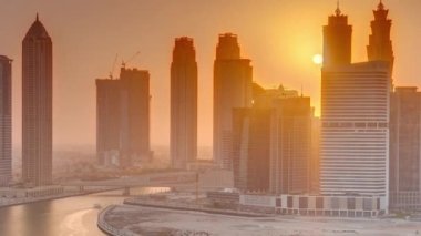 Dubai İş Körfezi 'ndeki gökdelenlerin günbatımında su kanallarının zaman ayarlı görüntüsü. Kuleleri ve limanı olan modern gökyüzü. Uluslararası bir iş merkezi.