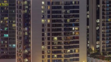 Pencereler, modern konut binalarında geceleri aydınlatılıyor. Parlayan ışıkları olan çok katlı gökdelenler..