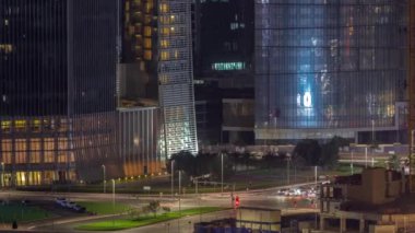 Dubai iş sahası bölgesi ofis gökdelenleri ve kavşağındaki yol kavşağındaki hava trafiği gece saat dilimi. İHA 'nın kavşağında hareket eden arabaların aydınlatma kulelerinde yansımalar