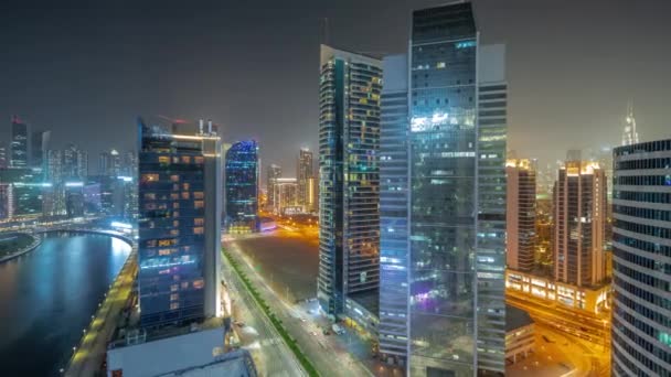 ドバイのダウンタウンとビジネスベイの高層ビルの都市景観と水上運河の空中夜のタイムラプス ライトアップされた塔やウォーターフロントとモダンなスカイライン 国際ビジネスの中心 — ストック動画