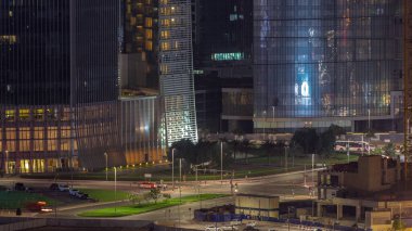 Dubai iş sahası bölgesi ofis gökdelenleri ve kavşağındaki yol kavşağındaki hava trafiği gece saat dilimi. İHA 'nın kavşağında hareket eden arabaların aydınlatma kulelerinde yansımalar