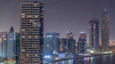 Dubai İş Koyu 'ndaki gökdelenlerin şehir manzarası. Su kanalı hava gece zaman çizelgesi boyunca. Aydınlatılmış kuleleri ve rıhtımı olan modern gökyüzü. Uluslararası bir iş merkezi.