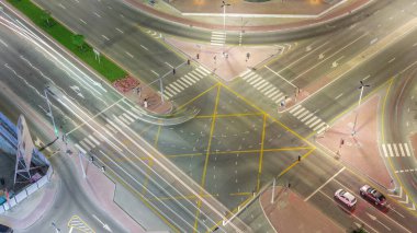 Dubai iş sahasındaki kavşakta yoğun trafik var. Hava sahasında gece uçuşu, BAE. Birçok otomobil ve otobüsün kavşağa doğru gidişine bakıyorum, BAE