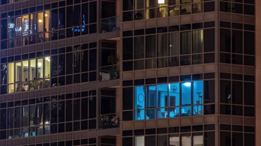 Modern şehir zaman diliminde geceleri gökdelenlerdeki ışık panoramik pencerelerle dolu. Parlak aydınlatma
