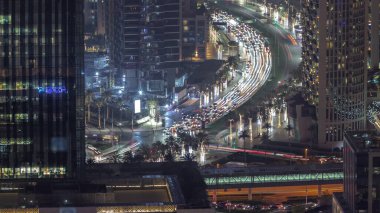 Dubai şehir merkezindeki kavşakta yoğun bir trafik var. Aydınlatılmış gökdelenler arasında bir çok araba kavşakta ilerliyor, BAE