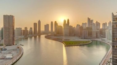 Dubai İş Körfezi 'ndeki gökdelenlerin günbatımında su kanalı panoramik zaman dilimi. Kuleleri ve limanı olan modern gökyüzü. Uluslararası bir iş merkezi.