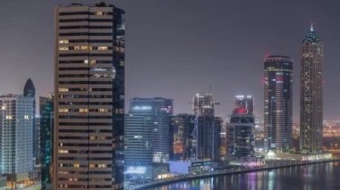 Dubai İş Koyu 'ndaki gökdelenlerin şehir manzarası. Su kanalı hava gece zaman çizelgesi boyunca. Aydınlatılmış kuleleri ve rıhtımı olan modern gökyüzü. Uluslararası bir iş merkezi.