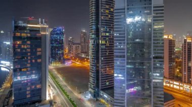 Dubai Business Bay ve şehir merkezindeki tüm gece boyunca su kanalları antenli gökdelenlerin manzarası. Aydınlatılmış kuleleri ve rıhtımı olan modern gökyüzü. Işıklar kapanıyor.