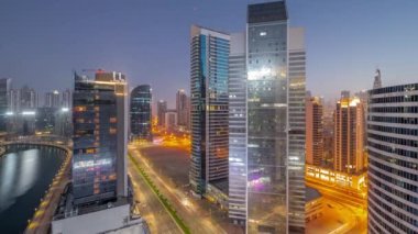 Dubai İş Körfezi 'ndeki ve şehir merkezindeki gökdelenlerin şehir manzarası. Gece gündüz su kanalları hava geçiş zamanı. Gündoğumundan önce aydınlık kuleleri ve rıhtımı olan modern gökyüzü.