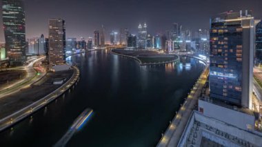 Panorama Dubai Business Bay 'deki gökdelenleri gösteriyor. Su kanalı gece zaman ayarlı. Aydınlatılmış kuleleri ve rıhtımı olan modern gökyüzü. Uluslararası bir iş merkezi.