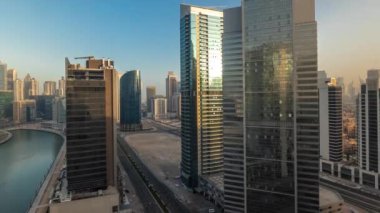 Güneşli şehir manzarası, güneş doğarken Dubai Business Bay 'in gökdelenlerinden yansıyor. Kuleleri ve limanı olan modern gökyüzü. Uluslararası bir iş merkezi.