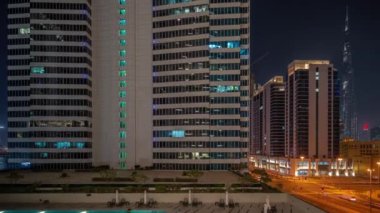 Hava panoramik görüntüsü Dubai şehir merkezindeki gökdelenlerin yoğun trafiği ile birlikte Business Bay semtindeki gece saat diliminde. Çatıda aydınlatılmış bir yüzme havuzu.