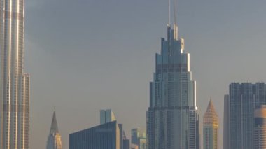 Şehir merkezindeki yüksek binalar ve Dubai, BAE 'deki finans bölgesi zaman çizelgesi. Güneş ışığı ışınlarıyla gün doğumunda gökdelenlerin cam yüzeyinden yansımalar