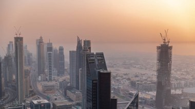Şehir merkezinin ufuk çizgisi, modern mimari biçimli, zaman çizgisinin üstünde. Dubai iş hangarı kulelerinin hava görüntüsü. Gökdelen gün batımında yapım aşamasında