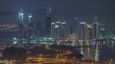 Dubai Creek Limanı 'nda gökdelenleri ve inşaat halindeki kuleleri gece vakti zaman ayarlı. Önplanda bir yol kavşağı