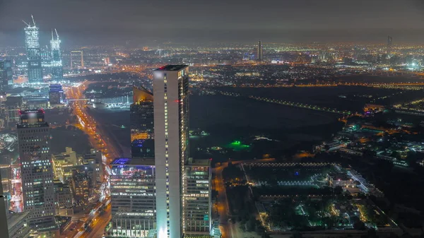 迪拜世界贸易中心区附近的摩天大楼和其他建筑物在迪拜的空中夜间全景时间过去了 公路交叉口的交通及由上往下泊车 — 图库照片