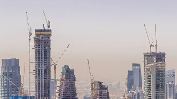 Dubai downtown with large-scale construction of a residential complex with a view of construction cranes aerial timelapse. Many towers and skyscrapers building progress