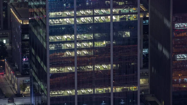 Illuminated panoramic windows in offices of a high class building at night timelapse. Glowing lights in skyscraper with open space