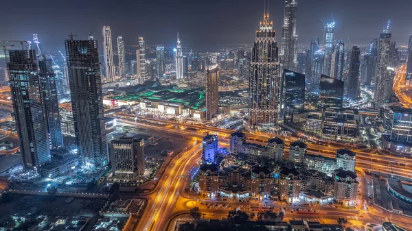 Downtown skyline with modern architecture form above night timelapse. Aerial view of Dubai business bay towers. Traffic on roads between skyscrapers and hotels