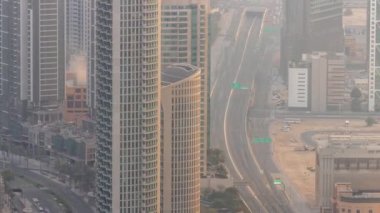 Dubai şehir merkezindeki yol kavşağında yoğun trafik var. Hava sisli gökdelenler arasında otoyolda giden birçok araba var, BAE