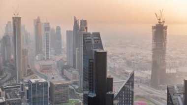 Şehir merkezinin ufuk çizgisi, modern mimari biçimli, zaman çizgisinin üstünde. Dubai iş hangarı kulelerinin hava görüntüsü. Gökdelen gün batımında yapım aşamasında