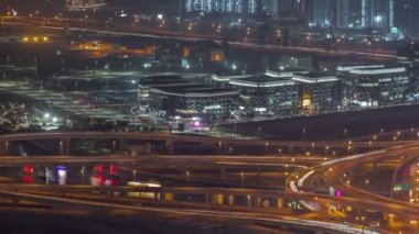 Dubai şehir merkezindeki üst geçit kavşağında yoğun trafik var. Arka planda dere bölgesinde inşaat alanı olan birçok araç kavşakta ilerliyor, BAE