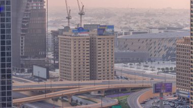 Büyük otoyol kavşağı ve Dubai su kanalı. Arka planda yaya köprüsü var. Gün batımında vinçler havada uçuşuyor. Birçok ev ve villa kavşağın arkasında..