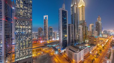 Dubai Uluslararası Finansal Bölgesi 'nin hava manzarası. Gün batımından sonra birçok gökdelen ve gece geçiş zamanı var. Çatıda yüzme havuzu olan çok katlı otoparkın yakınındaki bir yolda trafik vardı. Dubai, BAE.