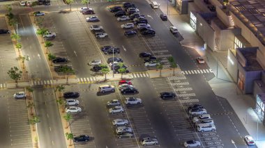 Bir otoparkta park halindeki sıra sıra arabaları gece vardiyasından izlenen kuyruklar arasında. Dubai 'deki alışveriş caddesi yakınlarındaki finans bölgesinin havadan görüntüsü