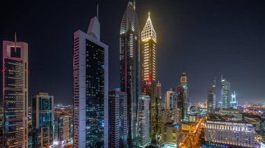 Dubai Uluslararası Finans Bölgesi 'nin panoramik hava manzarası ve birçok gökdelen gece zaman çizelgesi. Meşhur kulelerin yakınındaki yolda trafik vardı. Dubai, BAE.