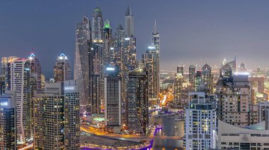 Dubai Marina hava sahasının en yüksek bloğundaki çeşitli gökdelenlerin görüntüsü suni kanalla gündüz gece geçiş zamanı. Gün batımından sonra birçok kule ve yat