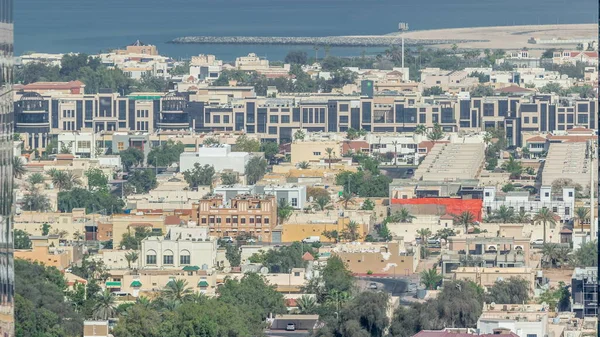 Aerial view of apartment houses and villas in Dubai city timelapse from skyscraper in financial district, United Arab Emirates. Recidential area with palms and trees