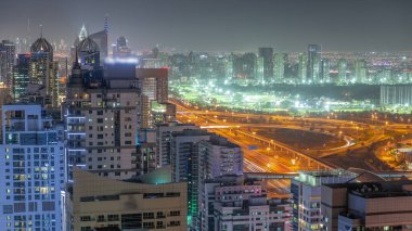 Dubai 'de lüks bir semt ve golf kulübü gece saatleri var. Dubai marina gökdelenleri yakınlarındaki kulelerin ve yol kavşağının havadan görüntüsü
