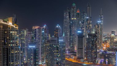 Dubai Marina hava sahasının en uzun bloğundaki çeşitli gökdelenlerin görüntüsü suni kanallı gece zaman ayarlı. Parlayan pencereleri ve yatları olan pek çok kule
