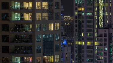 Parlak panoramik pencereli dış apartman binasının gece görüşü. Işıklı gökdelenle aydınlatılmış yüksek bir gökdelen