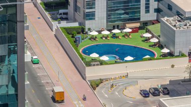 Çatıdaki yüzme havuzu, Dubai marinasındaki havuz manzarası. İnsanlar şemsiyelerin altında yüzüyor ve dinleniyorlar. Yollarda trafik vardı. Dubai, BAE